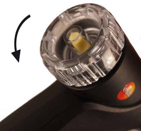 Transparent filter chamber on the testo 310 II flue gas probe, with the manual arrow showing an anticlockwise opening turn.